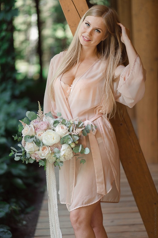 Пара рука об руку смотрят на закат через ветви дерева в очаровательном месте, покрытом цветущими растениями