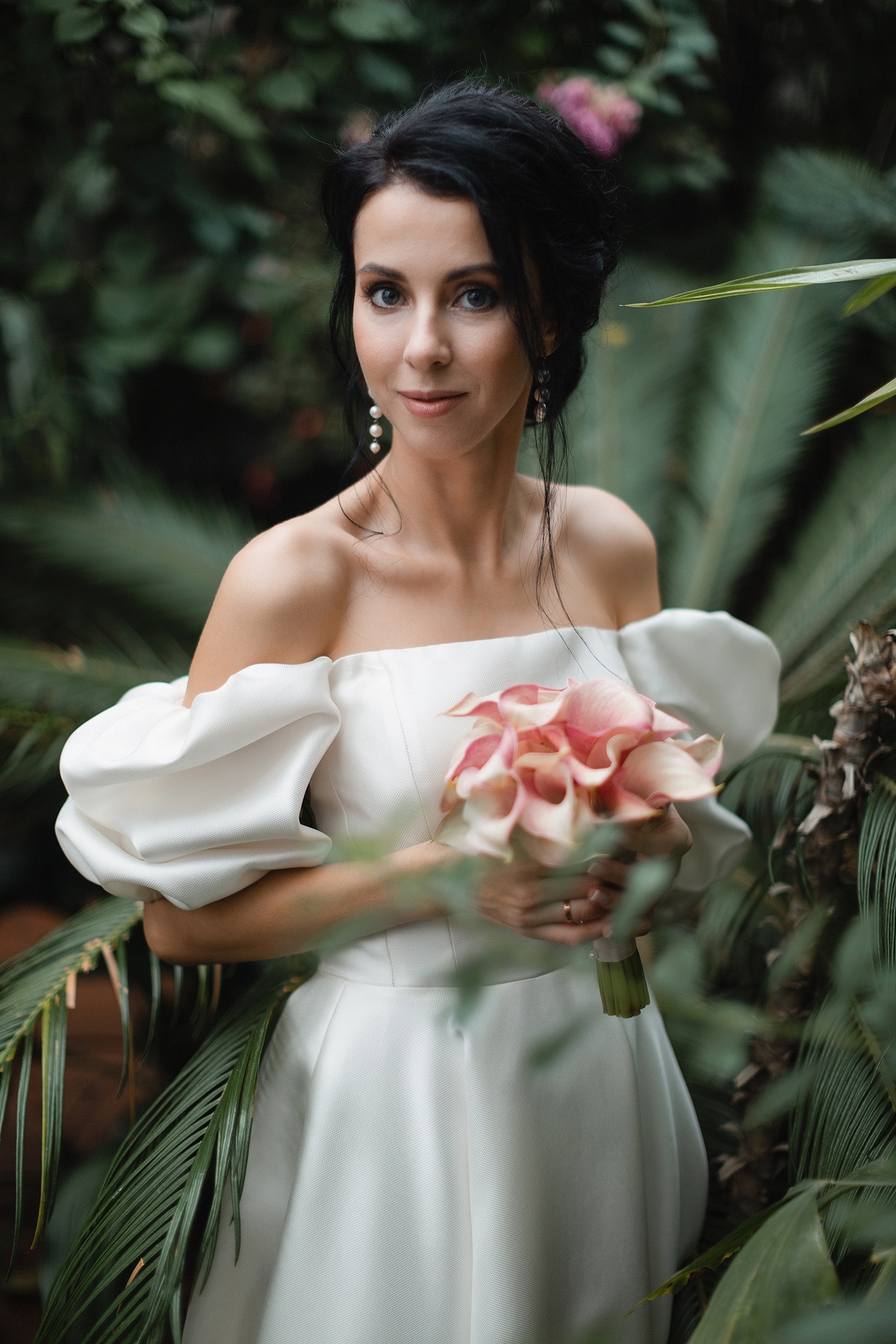 Свадебная фотография с невестой, стоящей на вершине горы, а жених держит ее за руку, создавая ощущение долговечности и преодоления