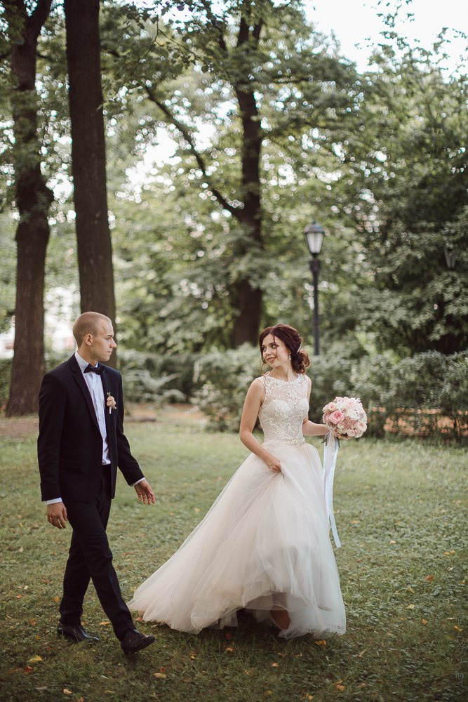 Невеста, сидящая на лавке в парке, с распущенными волосами и легким ветром, проносящимся