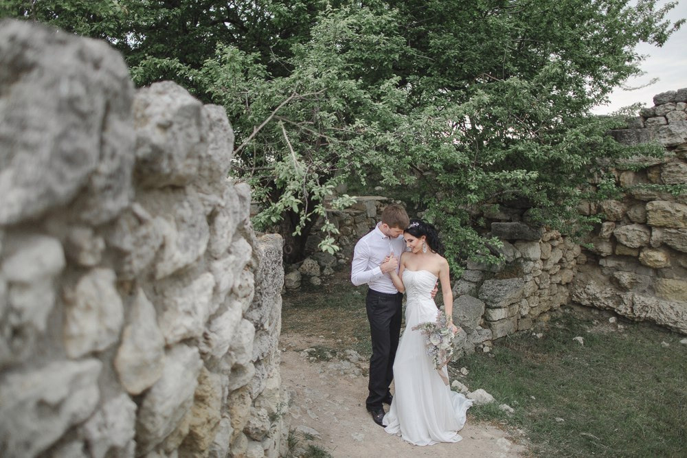 Молодожены на фоне дворца в Ярославле, идущие по дороге, усыпанной лепестками цветов, в их руках фонарики