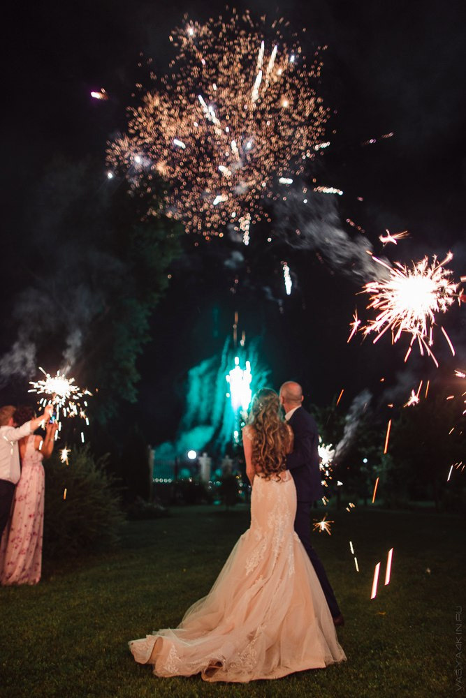 Улыбающаяся невеста и ее жених, которые бегут по песку на закате, обгоняя время