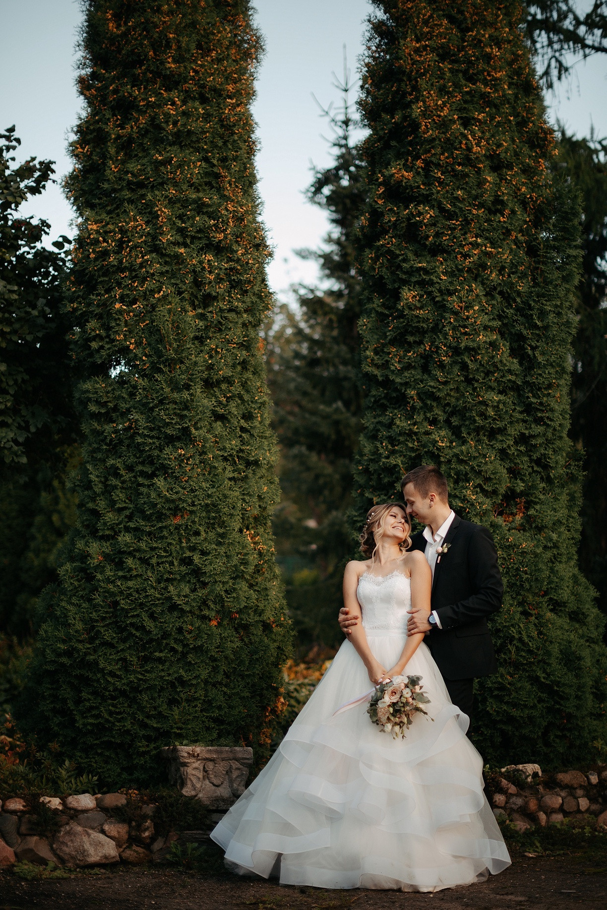 Свадебная фотография с невестой, улыбающейся под дождем, а жених прикрывает ее от непогоды, создавая ощущение защиты и заботы