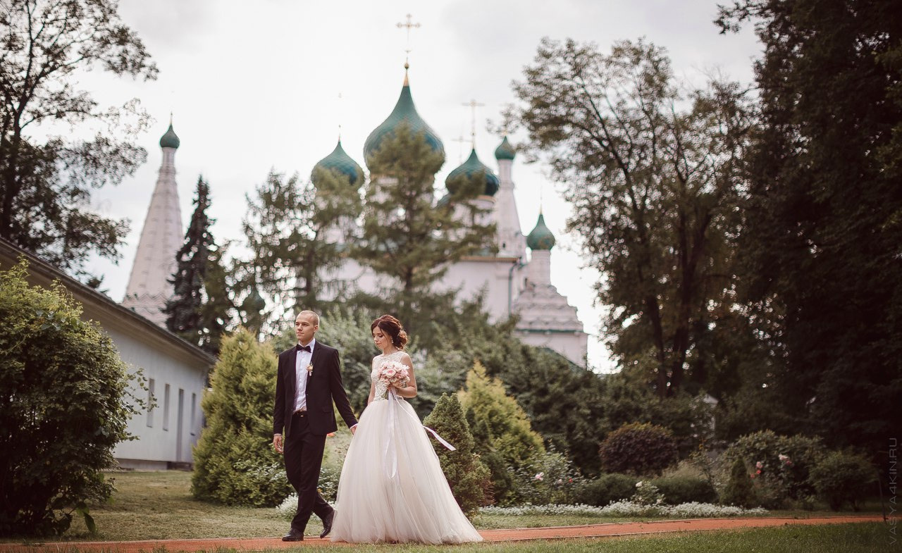 Новобрачные держат в руках деревянное сердце с вырезанной заставкой свадьбы, создавая фото идеального запечатления их любви