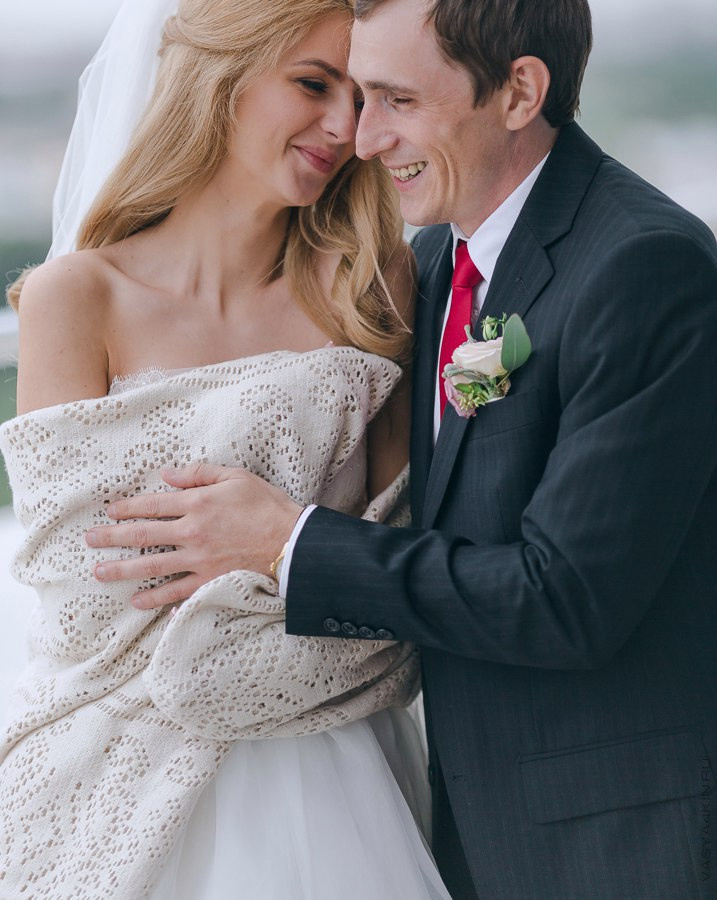 Невеста и жених смотрят друг на друга сквозь стеклянную дверь теплицы, на фоне множества цветов, словно обещая ухаживать друг за другом и сохранять любовь свежей и живой