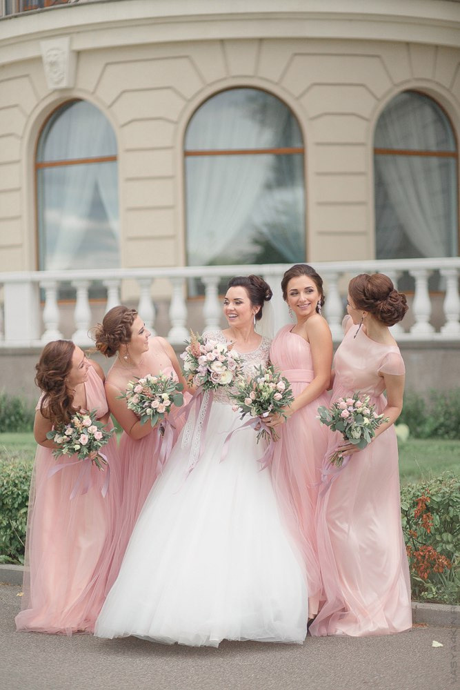 Снимок, на котором невеста и жених, прижимающие руки друг к другу, стоят рядом с рекой и наслаждаются взглядом на воду, создающую ощущение умиротворения и спокойствия