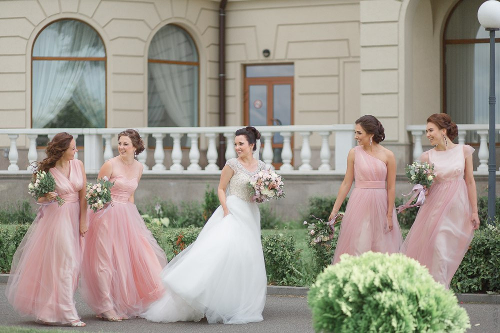 Фотография с дорогой свадьбы в Ярославле, где невеста и жених идут по дорожке, усыпанной белыми розами, в их руках пышные букеты