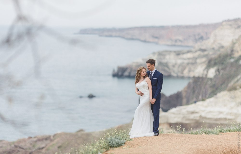 Пара, влюбленно сидящая на скамейке в прекрасном саду со статуями ангелов и дев