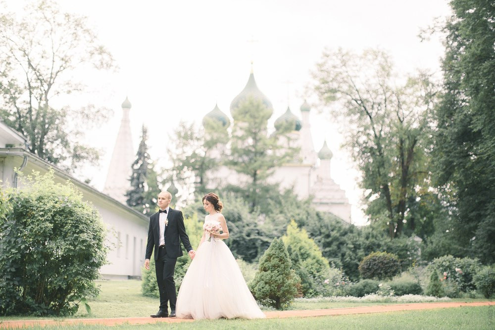 Снимок, на котором невеста и жених лежат на пикнике, окруженные цветами и фруктами, создавая атмосферу праздника и удовольствия