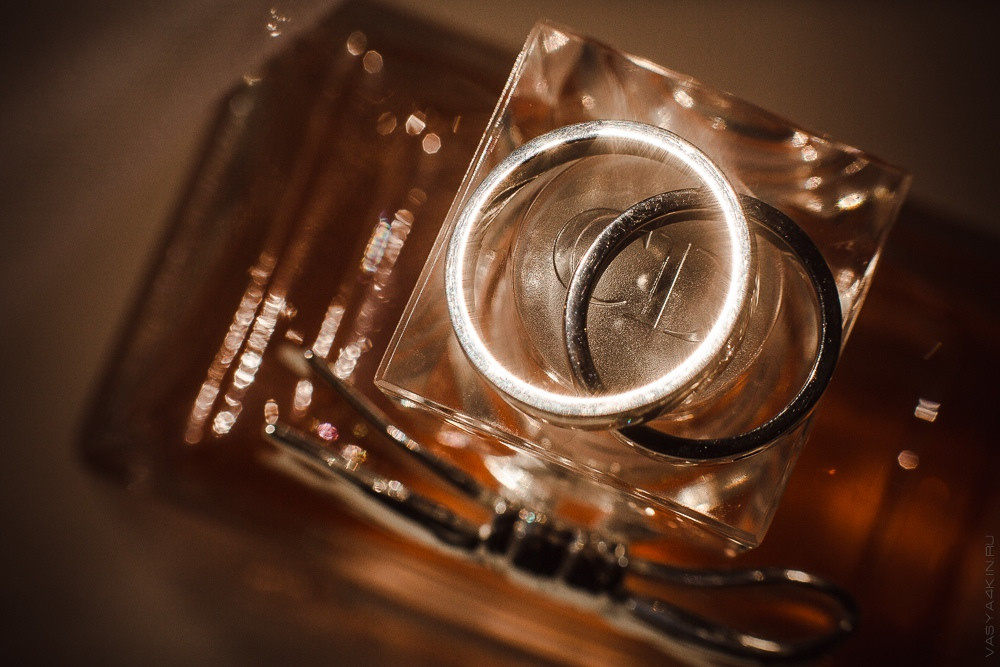 Пара целуется на пирсе, окруженном иллюминацией вечерних фонарей, отражающихся в мирном озере