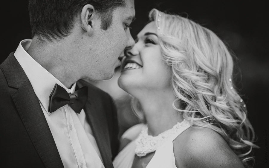 Снимок, на котором невеста и жених лежат на поляне, в окружении цветов и зелени, создающим ощущение покоя и спокойствия