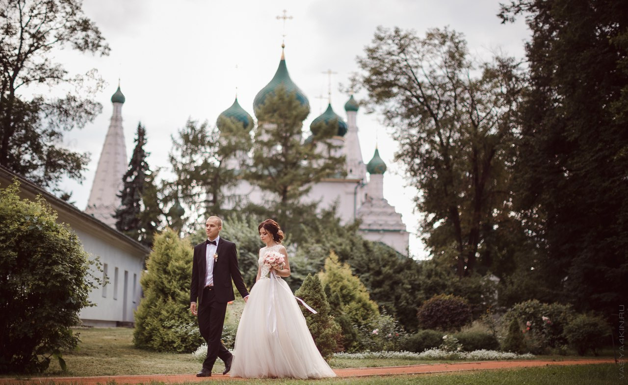 Невеста стоит на вершине холма, смотрящая на заходящее солнце, словно вся природа радуется их общему счастью на этой вдохновляющей свадебной фотографии