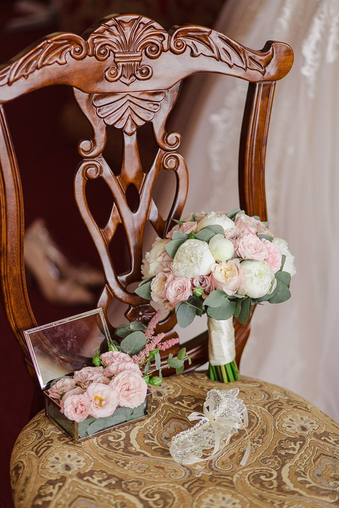 Невеста в белом платье и жених в черном смокинге идут по дорожке, обрамленной золотистыми столбами, на гламурной свадьбе в Ярославле