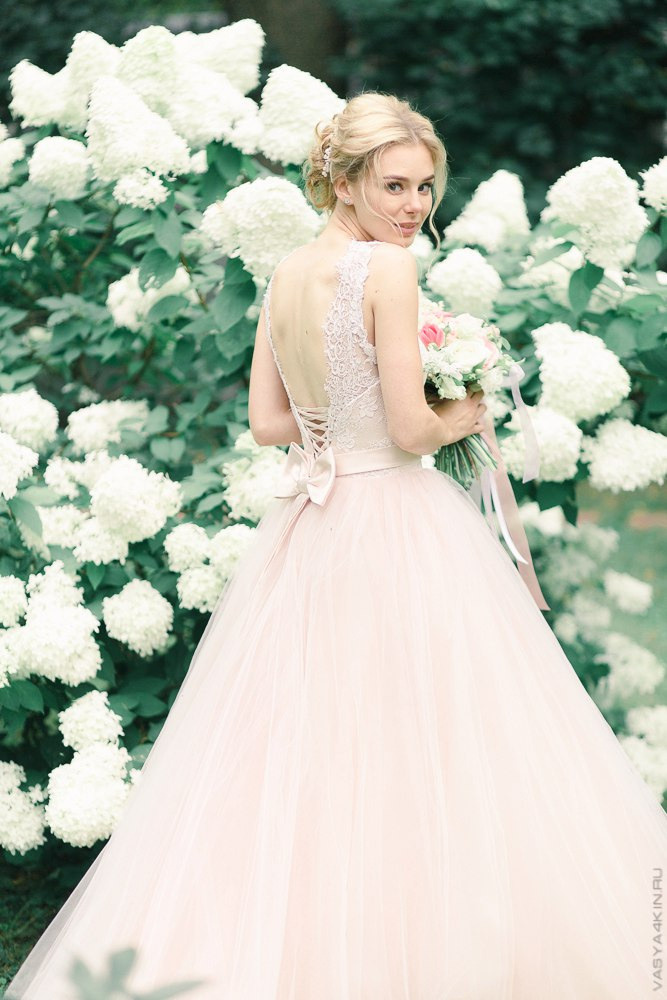 Невеста держит руку жениха, словно поддерживая его во всем, на этой свадебной фотографии