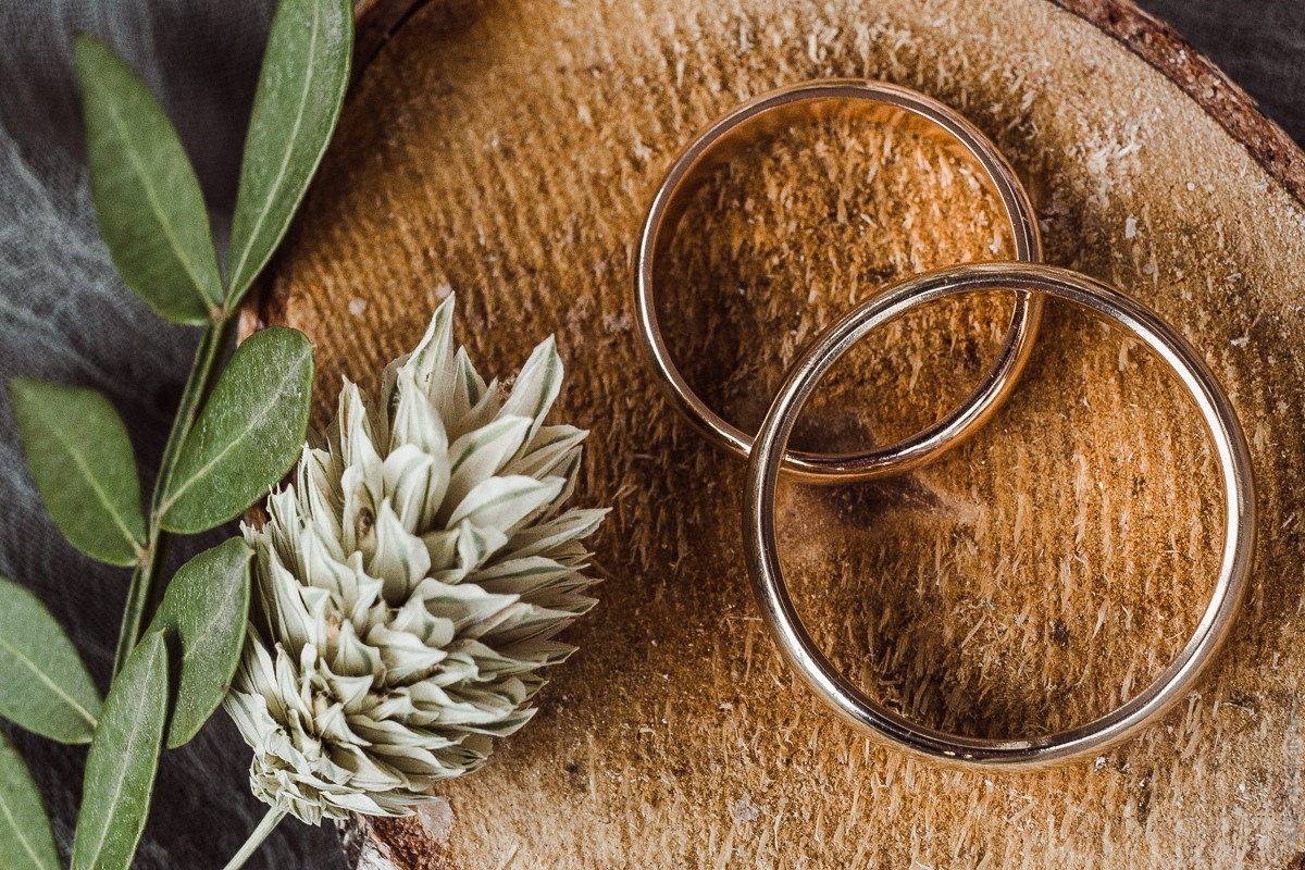 Снимок, на котором невеста и жених целуются на поляне, усеянной яркими цветами, создающими атмосферу веселья и беззаботности