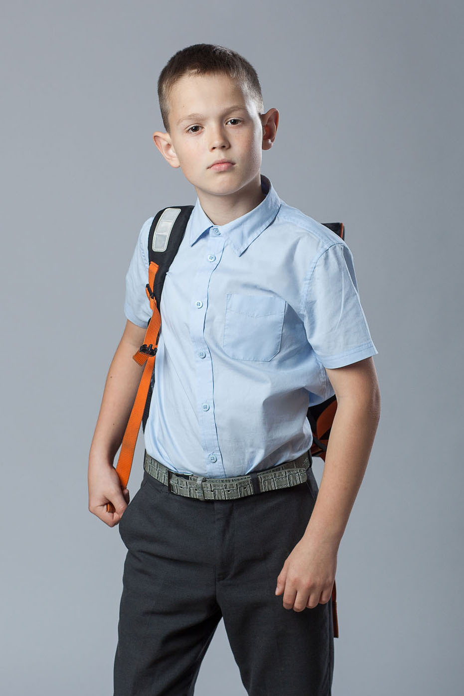 Студийный портрет выпускника  4 класса на сером фоне по пояс