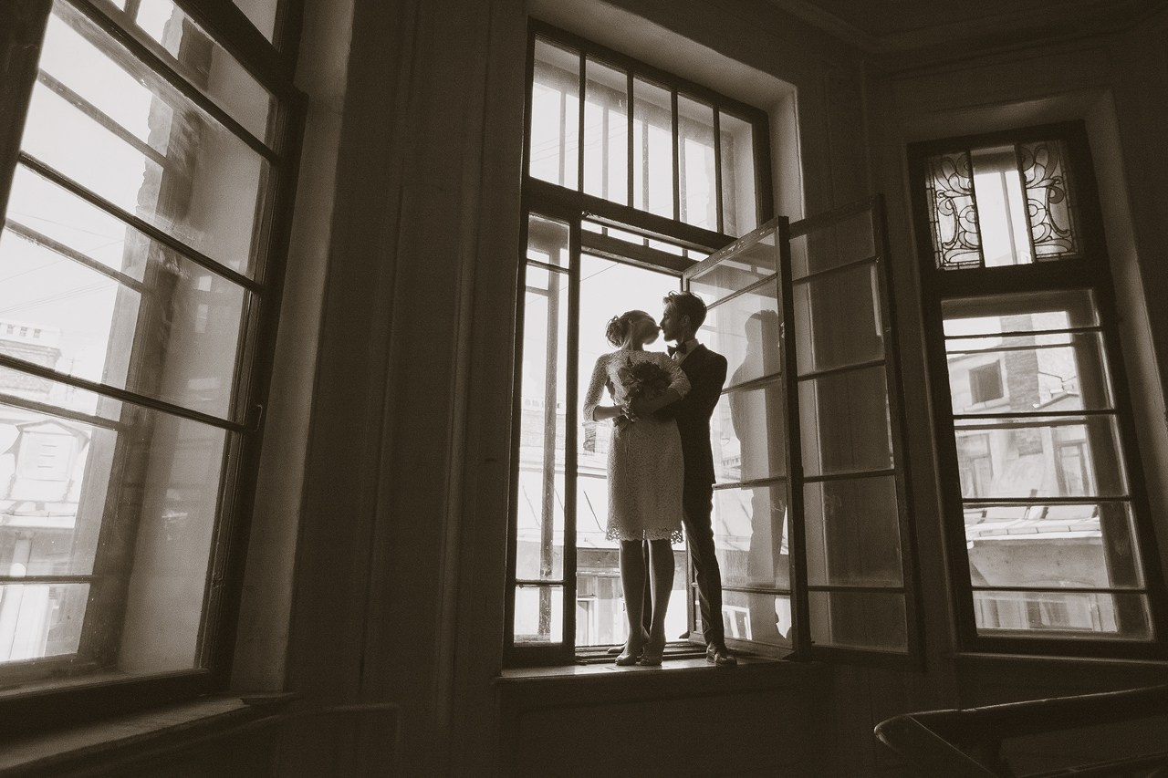 силуэты молодоженов в петербургской парадной у открытого окна