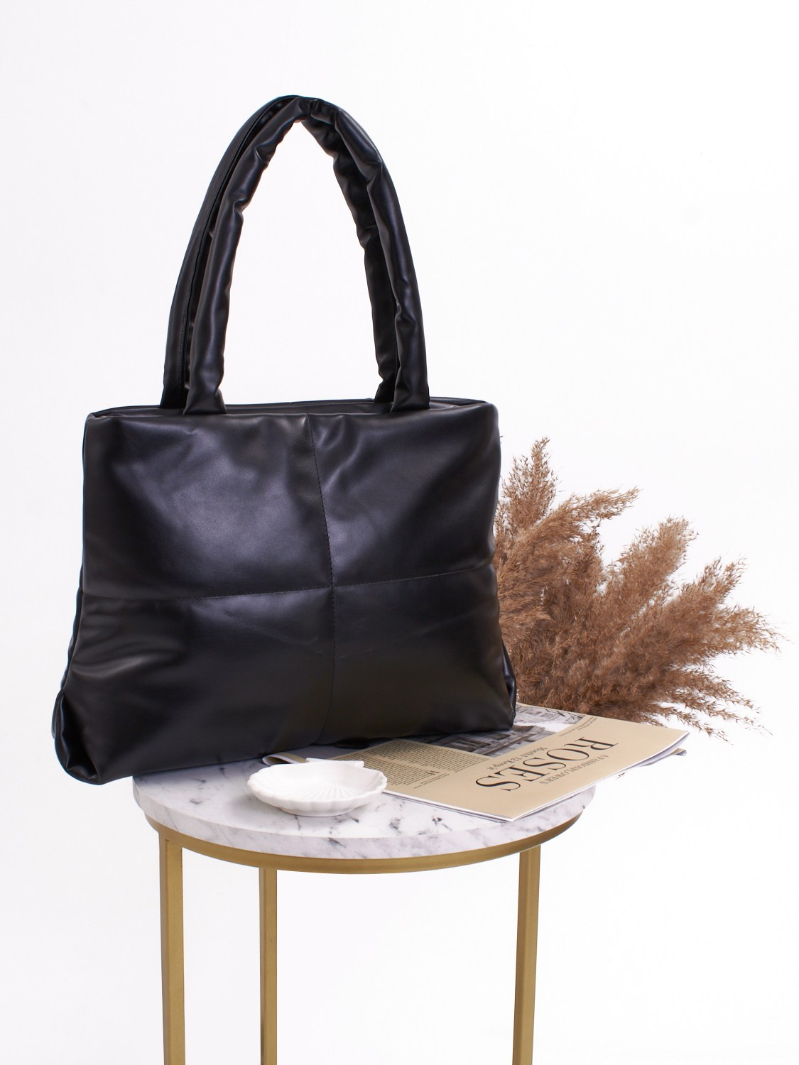 Мягкая черная сумка на маленьком столике и колосьями на фоне