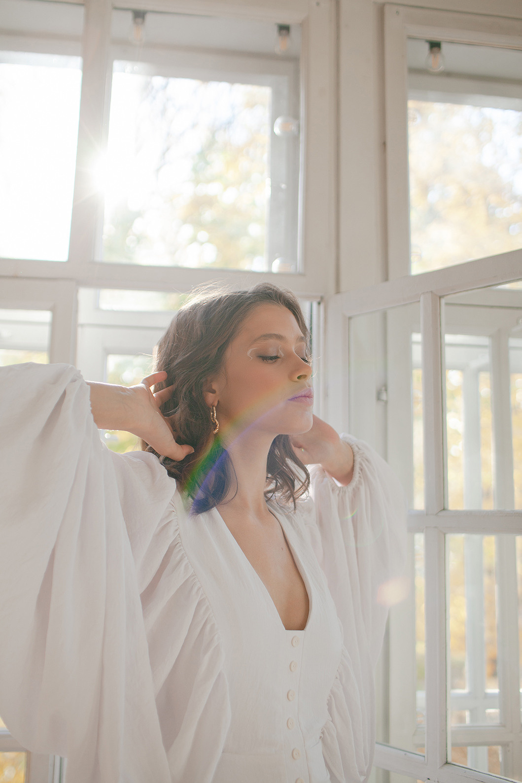 портрет девушки в белой одежде на фоне окон с бликами