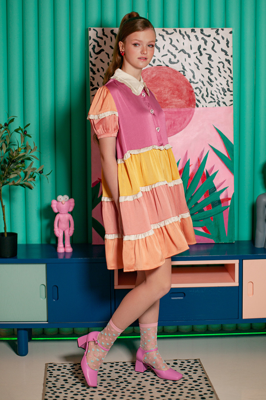 Девушка в платье в стиле 50-х годов стоит на фоне изумрудной стены в зале фотостудии