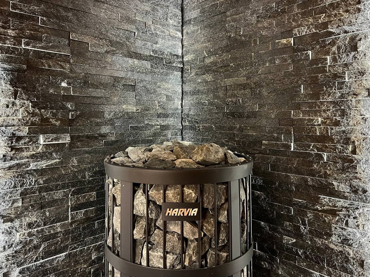 Просторная сауна в Сертолово из термоольхи с интеграцией можжевеловых линий и большого количества натурального камня. SaunaTopMasters