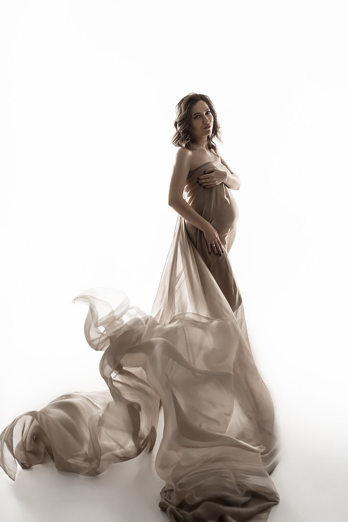 фотосессия беременной в фотостудии на светлом фоне в красивом разлетающемся платье, фотография беременности, фотосессия беременных, портрет беременной
