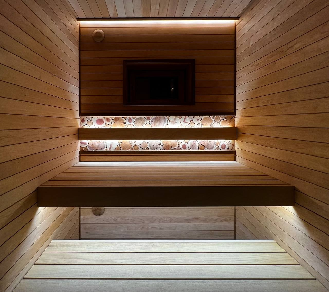 Компактная баня в Терра-Выборгском: светлая ольха в горизонтали и абаш на парящих полках визуально расширяют пространство. SaunaTopMasters