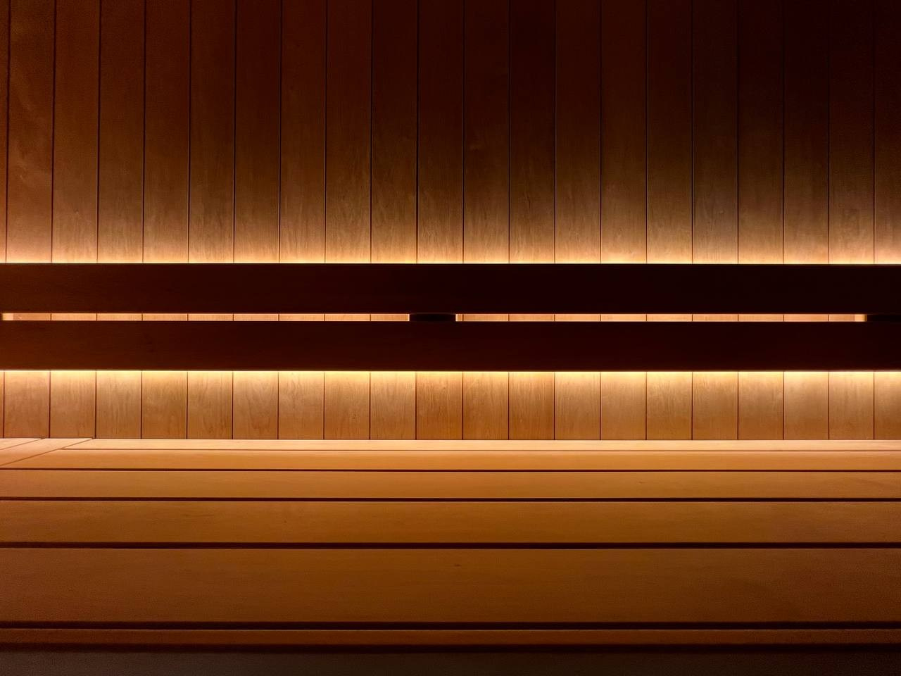 Уютная парная в Колтушах: внутренняя топка, печь в редкой облицовке, термоольха и тёплая линейная подсветка. SaunaTopMasters