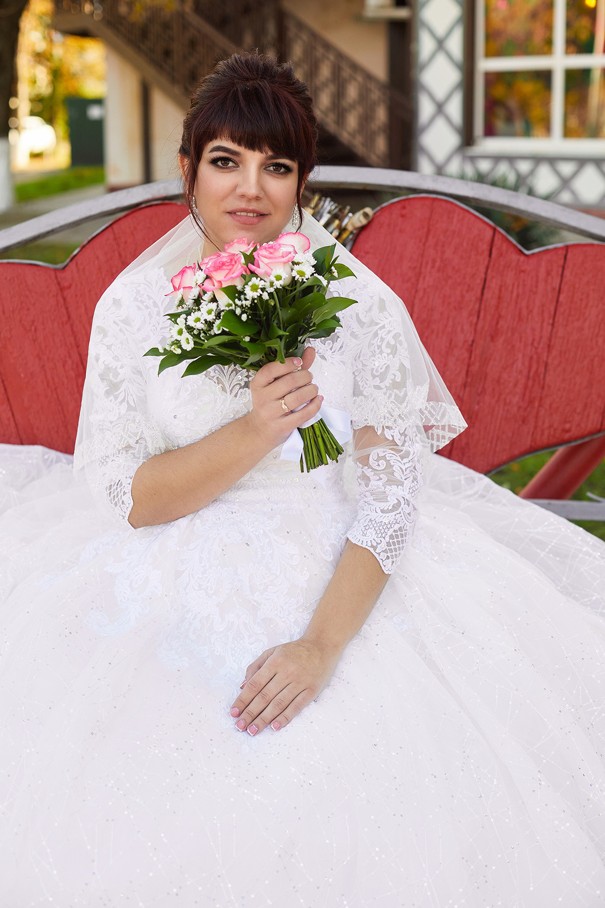 Невеста с букетом цветов сидит на скамье влюбленных в парке. Фотограф. Тимашевск. Кубань. Краснодарский край.