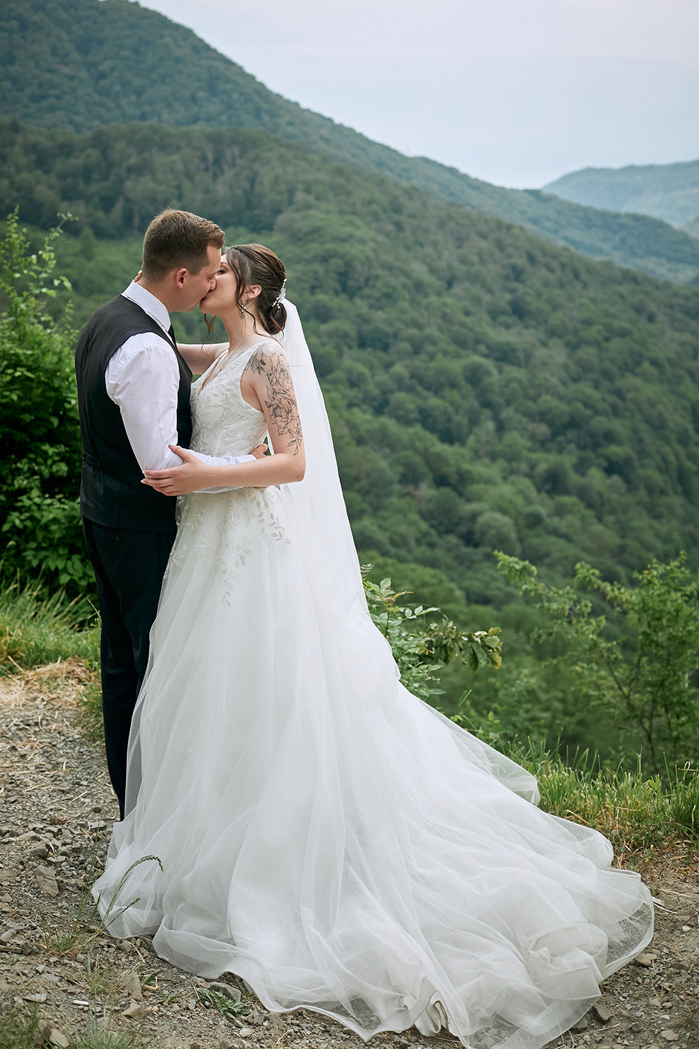 Невеста и жених целуются на краю обрыва на фоне гор. Фотограф. Тимашевск. Кубань. Краснодарский край.