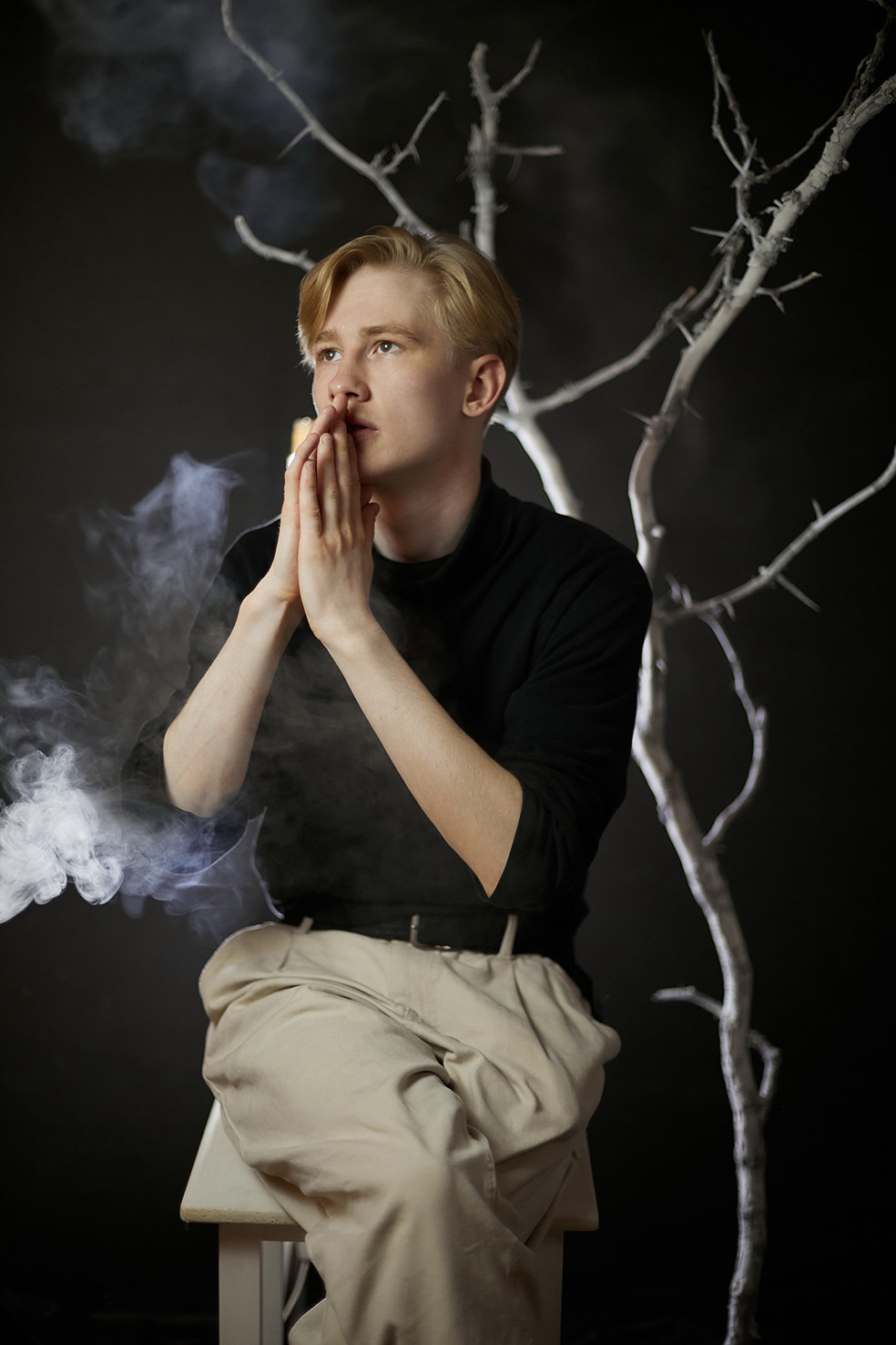Парень сидит на белом стуле на фоне белого сухого дерева на черном фоне. Фотограф. Тимашевск. Кубань. Краснодарский край. Москва. Фотограф в Москве.