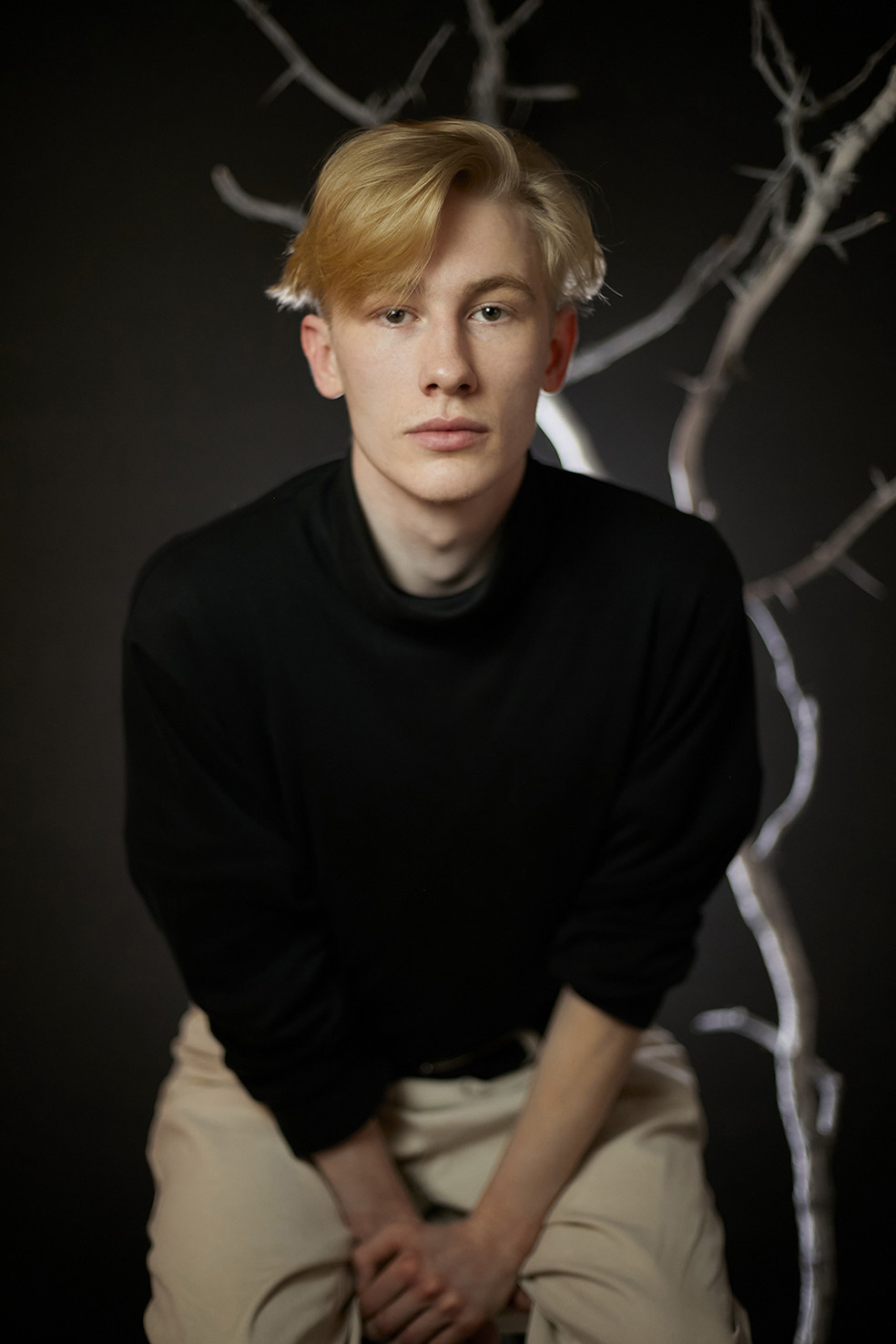 Парень сидит на белом стуле на фоне белого сухого дерева на черном фоне. Фотограф. Тимашевск. Кубань. Краснодарский край. Москва. Фотограф в Москве.