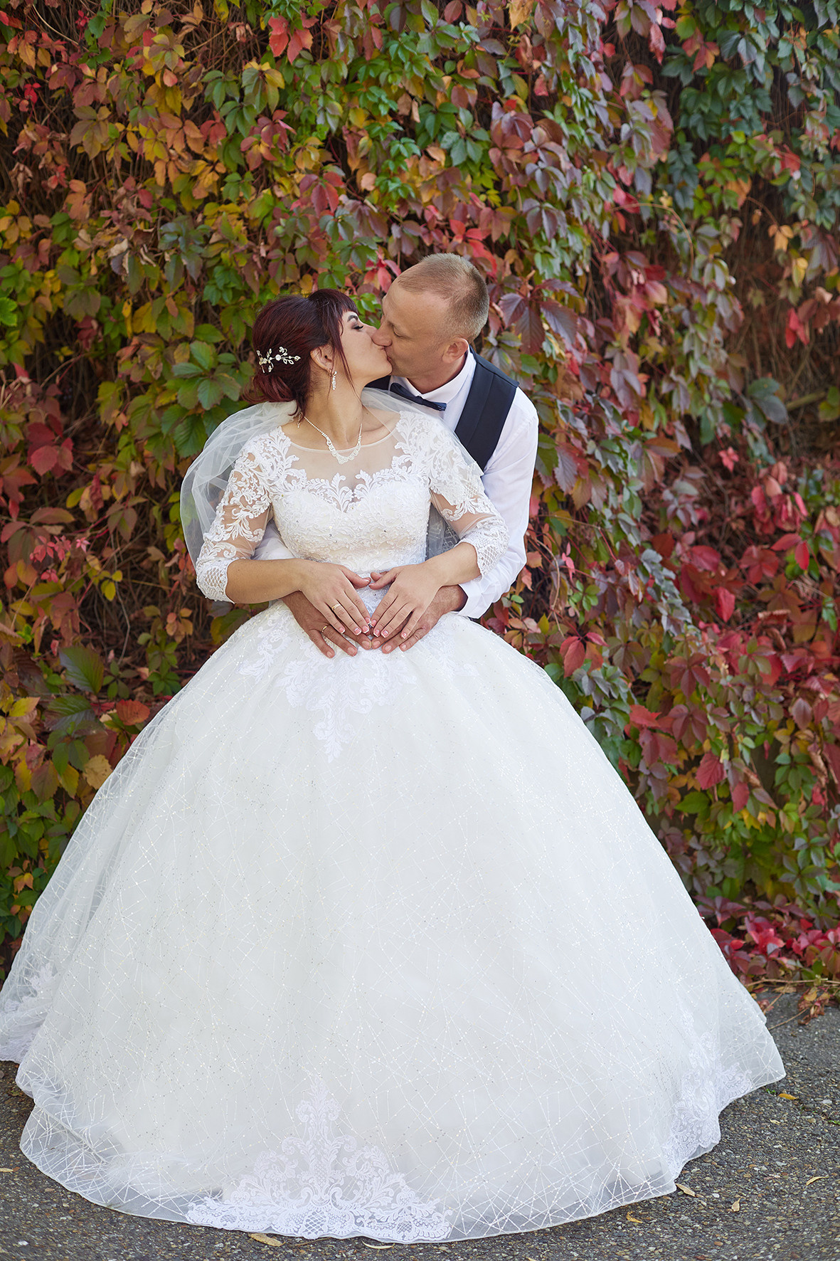 Невеста и жених целуются в парке на фоне вьющегося плюща. Фотограф. Тимашевск. Кубань. Краснодарский край.