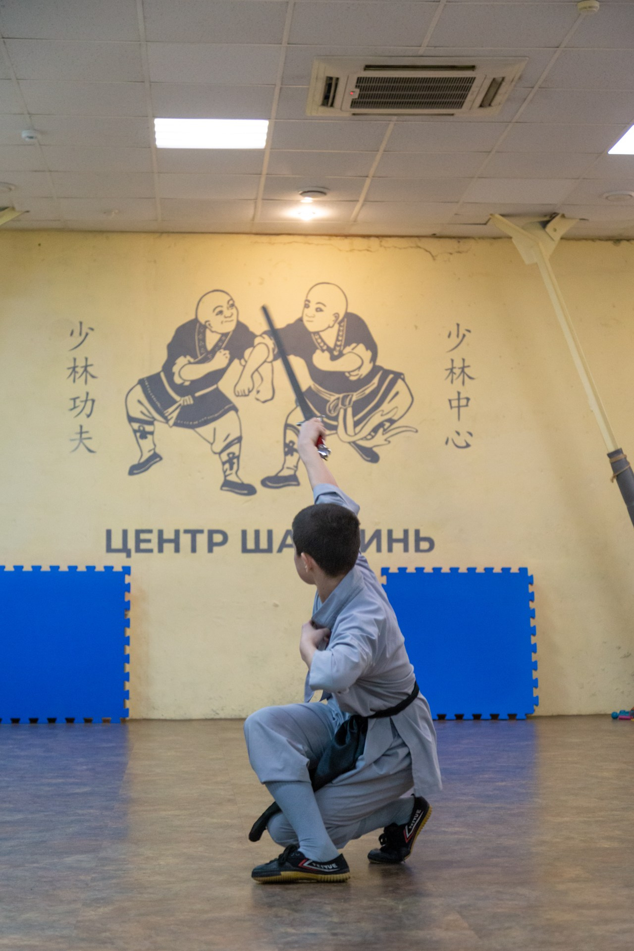 Надпись на желтой стене. Китайские иероглифы на стене. Парень с мечом цзянь. Комплекс с мечов в Воронеже.