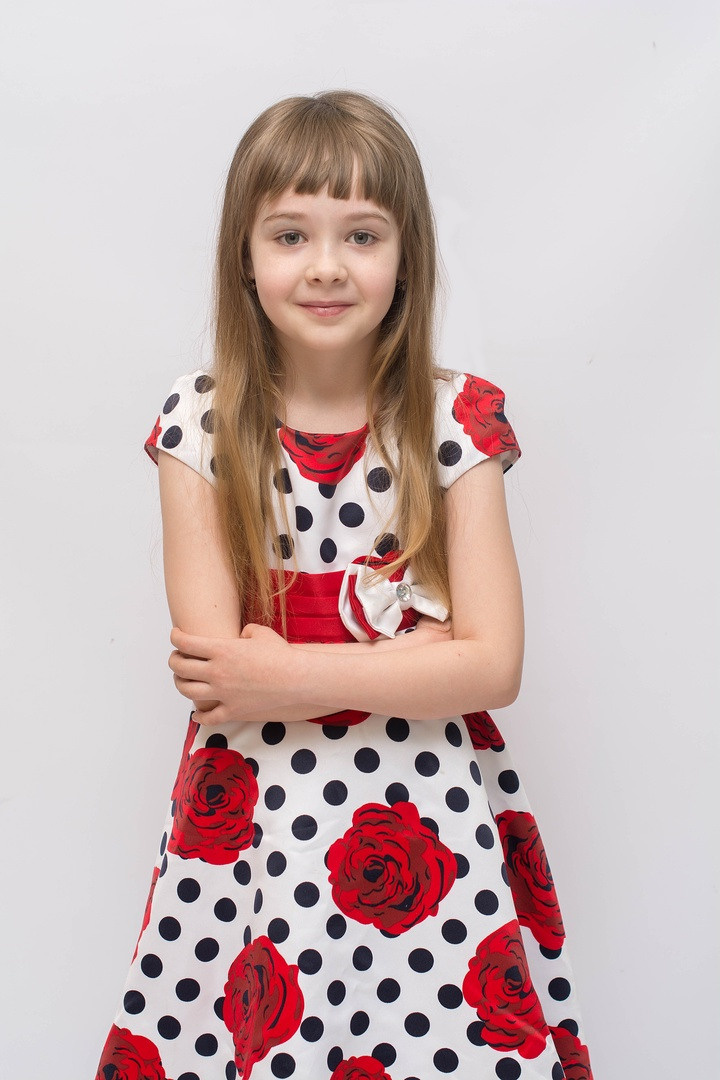 Девочка с длинными волосами в красивом красно-белом платье.