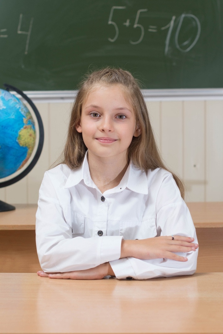 Юная отличница красиво сидит в классе.