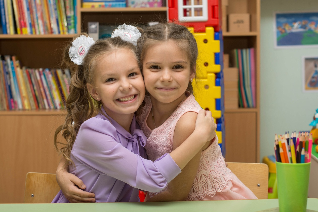 Детсадовские подружки сидят в  обнимку и мило улыбаются.