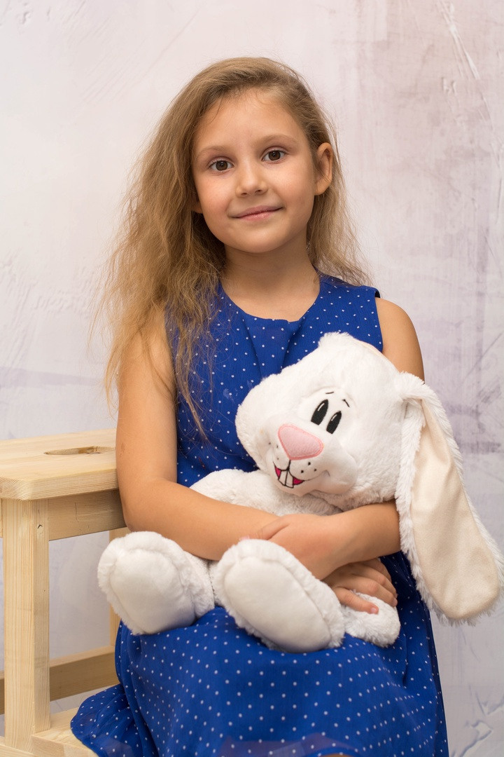 Фото ребёнка с мягкой игрушкой на стульчике.