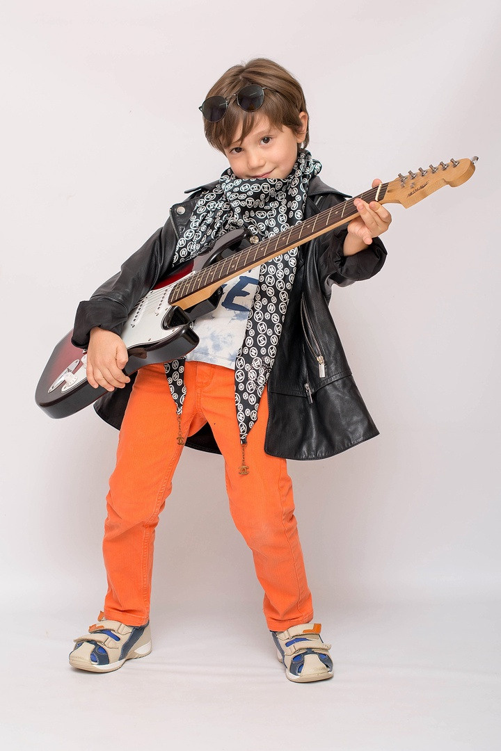 Крутяшный рок исполнитель позирует в  плаще с электрогитарой.