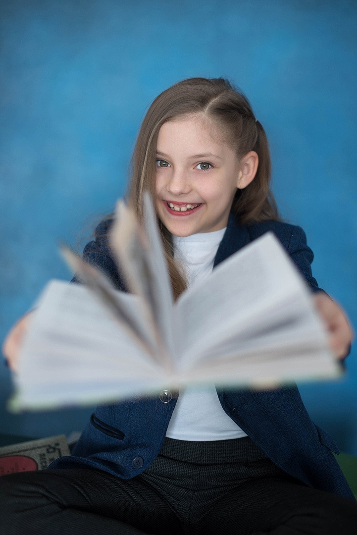 Девочка с раскрытой книгой на камеру.