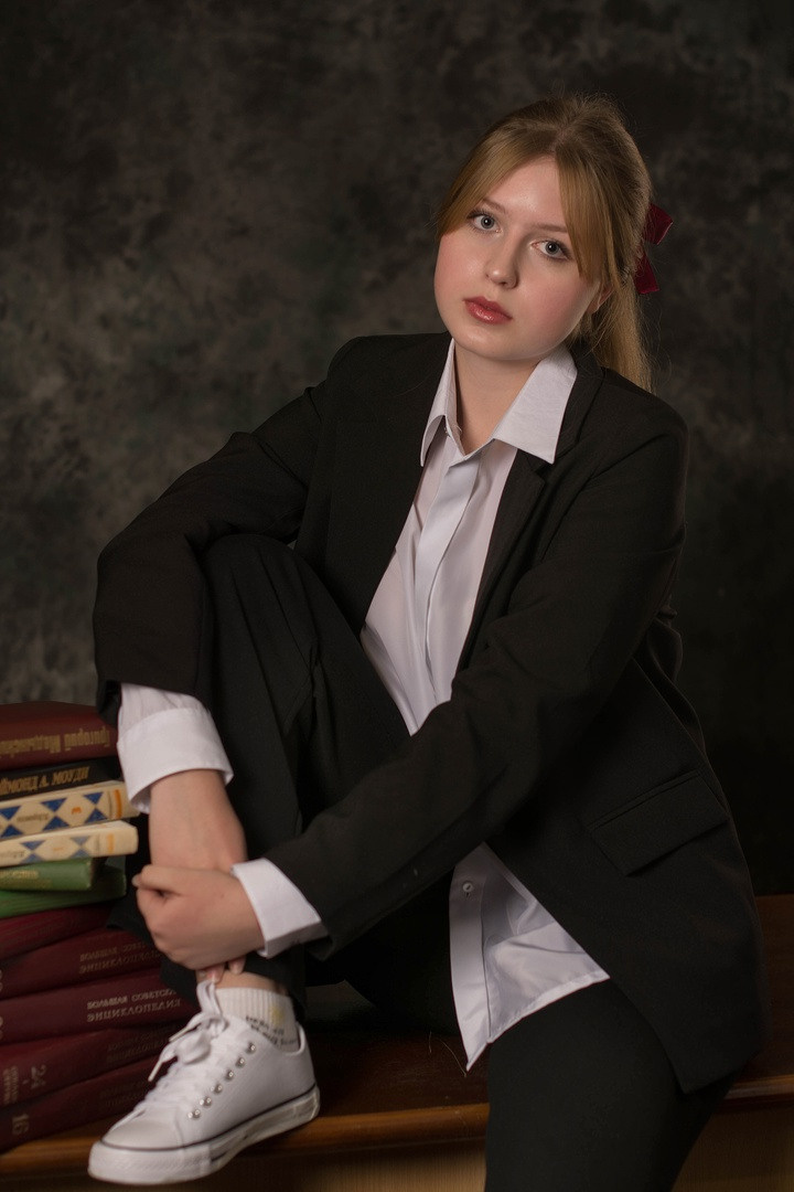 Симпатичная девушка на фото сидит на парте.