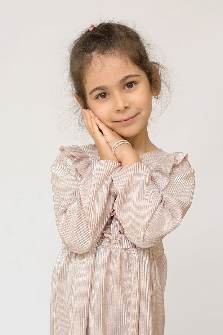 Одиноко стоящая маленькая мадам красиво держит ладошки у подбородка.