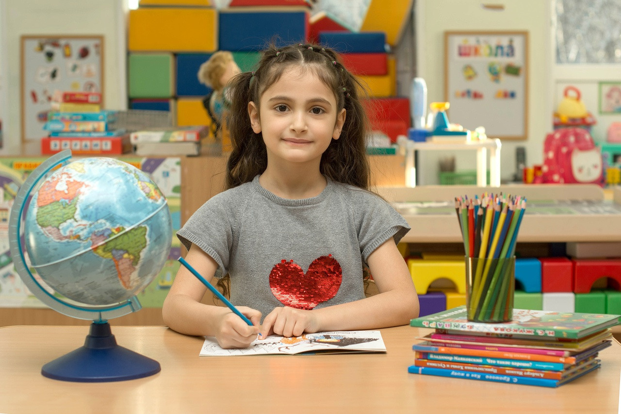 Игрушки на столе и канцелярские принадлежности на заднем плане.