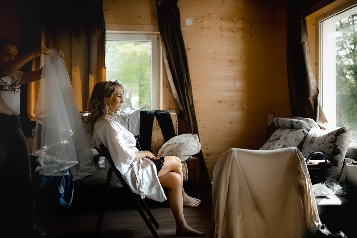 Сборы невесты. Невеста сидит в кресле во время макияжа в комнате в Санкт-Петербурге