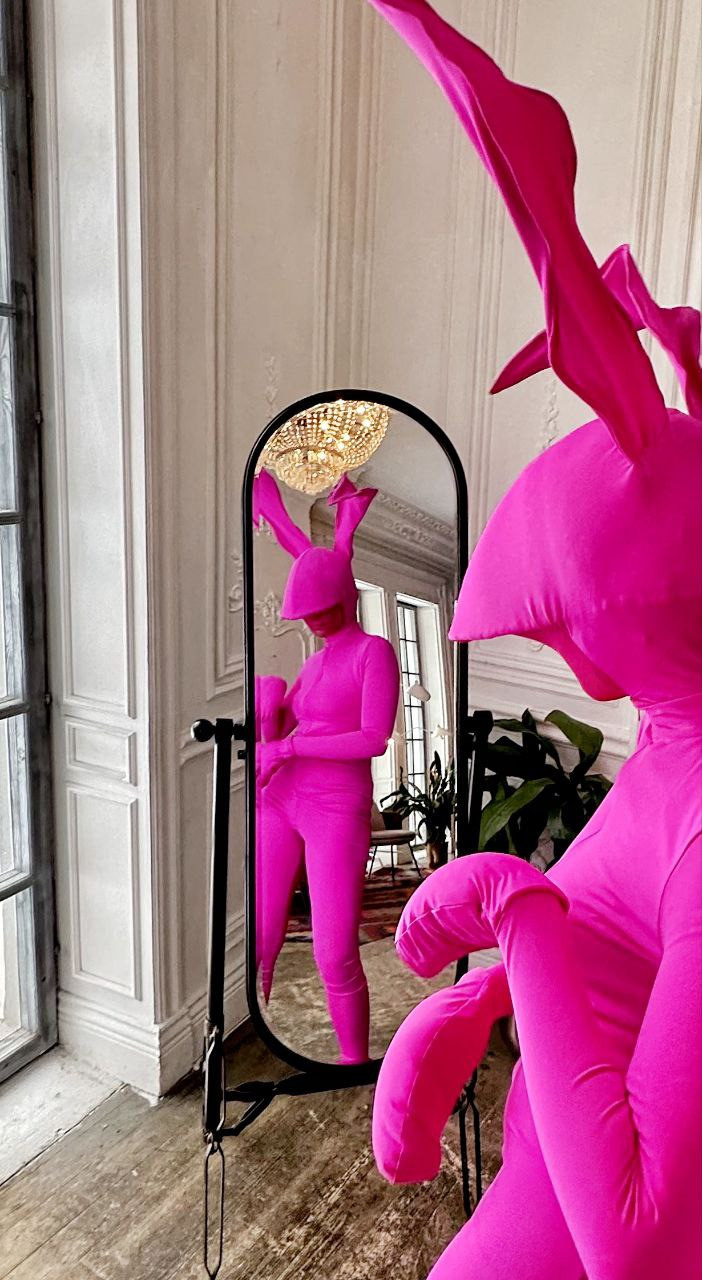 Сексуальная девушка зайчик в облигающем костюме смотрится в зеркало.