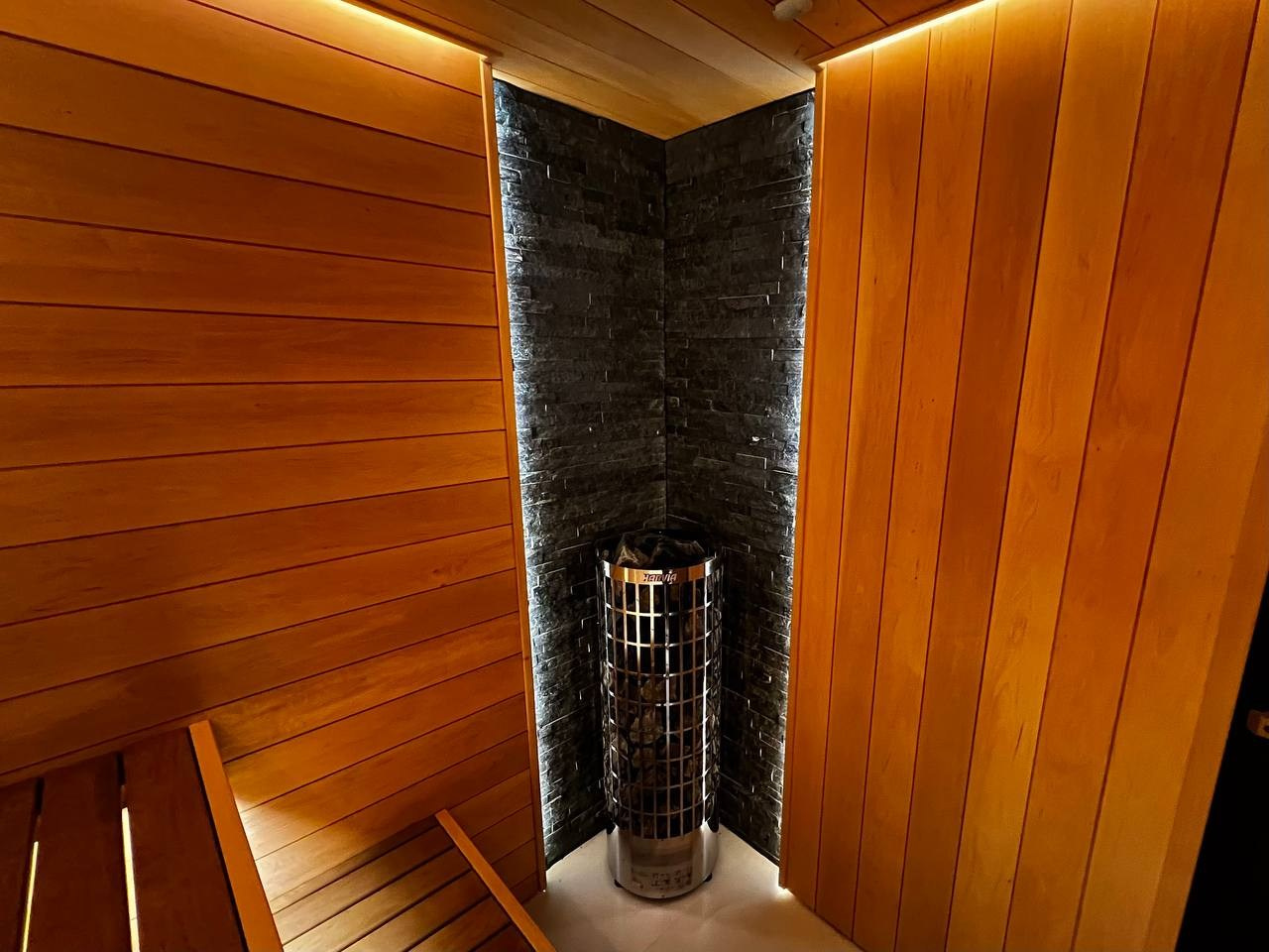 Уютная сауна в КП Новый Мир. В центре внимания- Harvia Cilindro, а закарнизное освещение плавно перетекает в подсветку противопожарного угла. SaunaTopMasters