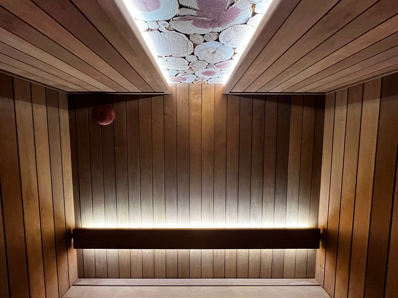 Компактная сауна в Охта Парке с электрокаменкой Harvia Cilindro, отделкой из термоольхи и сияющим можжевеловым панно. SaunaTopMasters