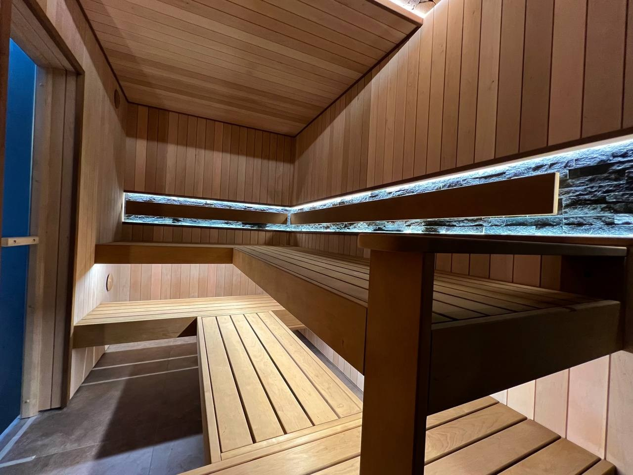 Просторная сауна в Сертолово из термоольхи с интеграцией можжевеловых линий и большого количества натурального камня. SaunaTopMasters