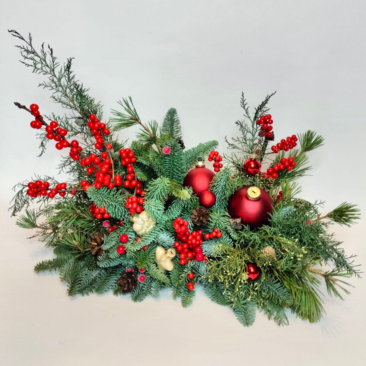 Композиция из натуральной хвои с ярко-красным илексом в современной флористике