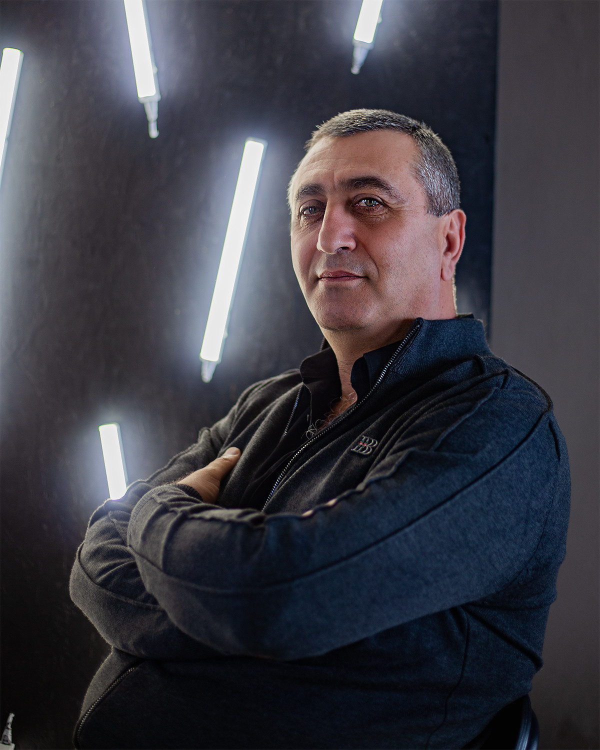 Мужской портрет сидящего мужчины на фоне осветительных приборов