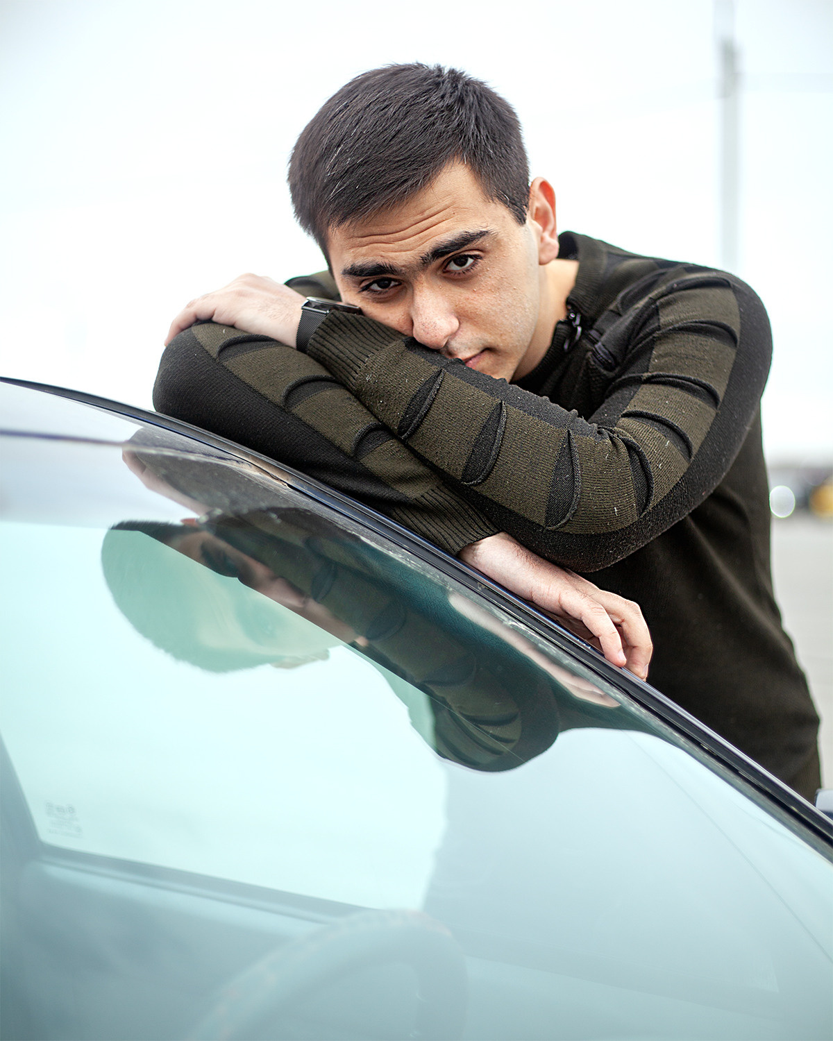 Молодой человек облокотился на кузов легкового автомобиля